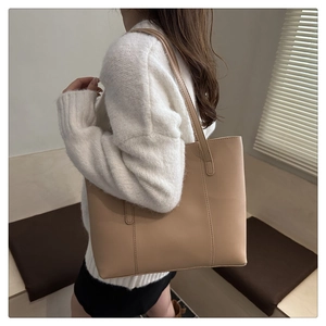 Detail of light brown tote bag with decorative stitching and long straps for daily commute