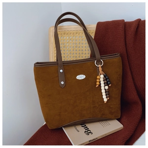 Détail du cabas marron mat avec pendentif en perles de bois et plaque en métal ovale