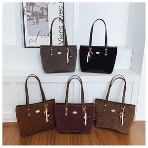 Collection de grands sacs cabas en cinq couleurs avec perles et logos sur socles blancs
