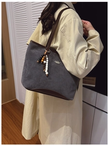 Détail du sac cabas en daim gris avec anses en cuir marron et pendentif à perles