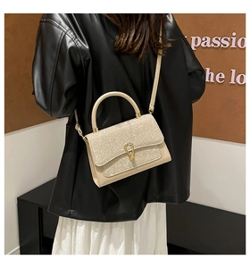 Detail of a creamy leather crossbody bag with a glitter flap shown on a model