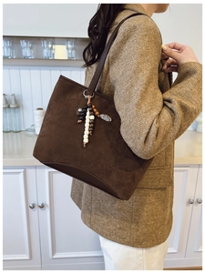 Détail d'un sac cabas en daim marron avec charme perlé et pendentif à motif léopard