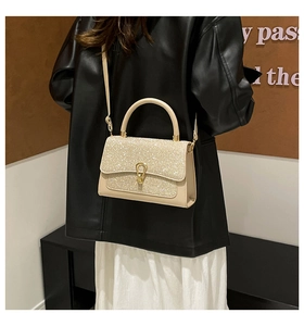 Detail of glittery champagne gold evening bag with metal lock and rhinestone surface