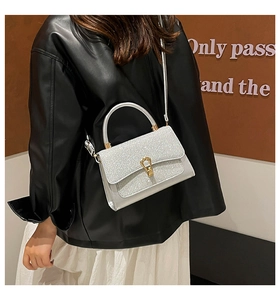 Detail of silver sequined crossbody bag with gold horseshoe buckle and elegant top handle