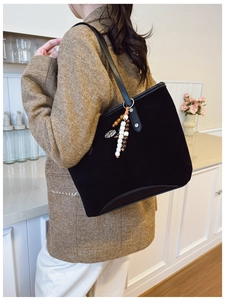 Détail du sac cabas en daim noir avec anses en cuir et pompon décoratif en perles ethniques
