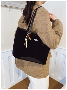 Détail d'un grand sac cabas noir avec pendentif en perles sur la bandoulière