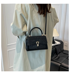 Détail du sac bandoulière en cuir noir avec rabat pailleté et fermoir en métal doré
