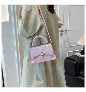 Detail of pink crossbody bag with sparkling glitter flap and gold horseshoe lock buckle