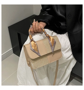 Detail of beige square handbag featuring gold sequin flap and scarf-wrapped top handle