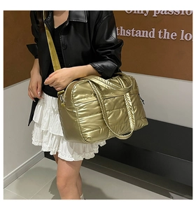 Detail der metallisch goldenen Stepptasche mit verstellbarem Nylon-Schultergurt und Griff