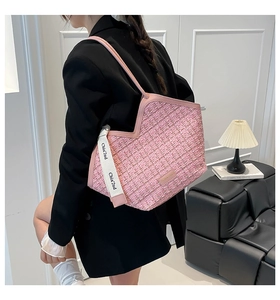 Detail of pink tweed tote bag with chic letter shoulder strap worn by a female model