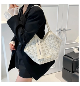 Close-up of beige tweed tote bag with leather trim and Chia 2nd printed strap details