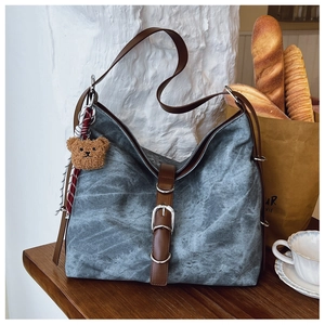 Detail of vintage tote bag featuring brown leather straps and a cute plush bear charm