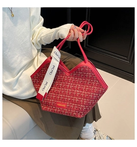 Close-up of red woven tote bag with V-shaped opening and lettered shoulder strap