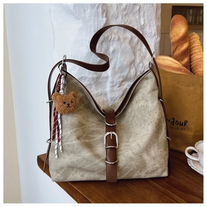 Vintage canvas tote bag detail with brown leather straps and cute plush bear charm