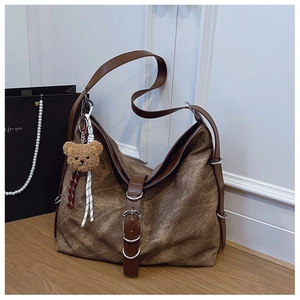 Detailed view of vintage brown tote bag with leather buckle and plush bear pendant detail