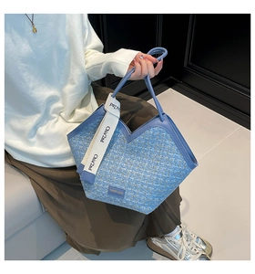 Detail of blue tweed tote with deep V-cut edge and branded wide crossbody strap