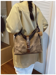 Detail of vintage brown suede tote bag with metal buckles and plush bear charm