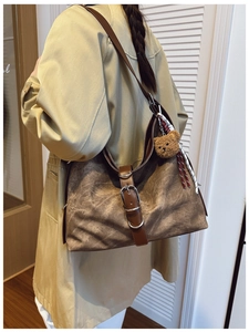 Detail of vintage brown oversized hobo bag with teddy charm and decorative buckle