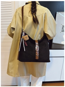Detail view of black suede tote bag with dark brown leather straps and metal buckle