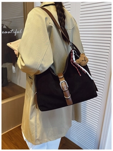 Detail of vintage large tote bag with brown straps and plush bear charm on model