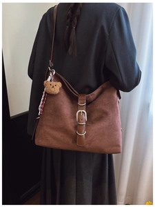 Detail view of vintage dark brown suede shoulder bag with plush bear and silk scarf decor