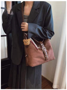 Detail of dark brown suede tote bag with metal buckle and cute bear charm pendant