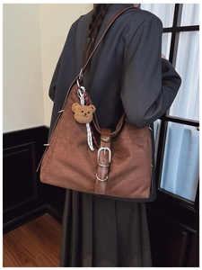 Detail of vintage brown tote bag with decorative buckle and cute plush bear charm