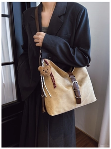 Detail of khaki suede tote bag featuring brown leather strap and cute plush bear charm