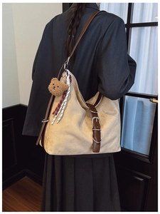 Detail view of large vintage tote bag featuring brown leather trim and bear charm