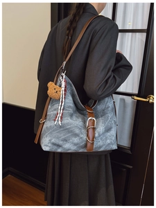 Detailed view of large grey canvas tote bag with brown leather straps on shoulder