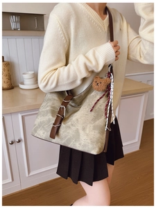 Detail of canvas tote bag with brown leather straps and cute teddy bear charm