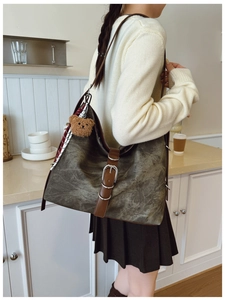 Detail of vintage canvas tote bag with leather straps, buckle, and plush bear charm