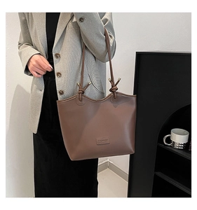 Detail of a large brown leather tote bag with knot strap and gold metal hardware
