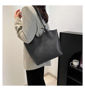 Detail of matte leather tote bag with FASHION embossed logo and knotted strap accents
