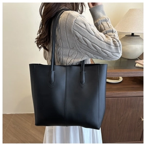 Detail of minimalist large black tote bag with stitching on a long shoulder strap