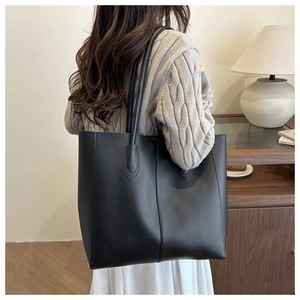 Detail of minimalist black tote bag with vertical stitching on matte leather finish