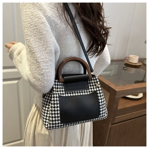 Detail of houndstooth crossbody bag with wooden handle worn by a model in lifestyle setting