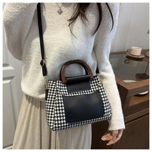 Close-up of houndstooth crossbody bag featuring round wooden handles and leather strap