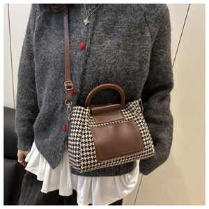 Detailed view of the vintage houndstooth texture and brown leather strap on the bucket bag