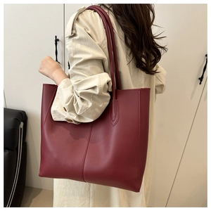 Deep red matte leather tote bag shown on model for a stylish shoulder carry look