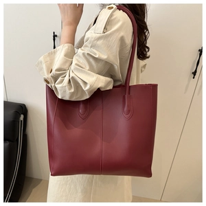 Detail of burgundy tote bag showing stitched texture and long handles for shoulder wear
