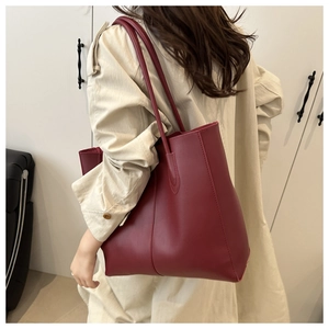 Deep red large capacity leather tote bag worn over the shoulder for winter styling