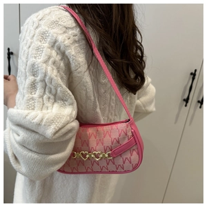Dettaglio borsa rosa con motivo monogramma M e chiusura in metallo dorato a cuore