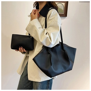 Close-up of minimalist black tote bag with shoulder strap knot and matching zipper pouch