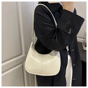 Close-up of a glossy beige hobo bag with detailed double stitching on the side profile