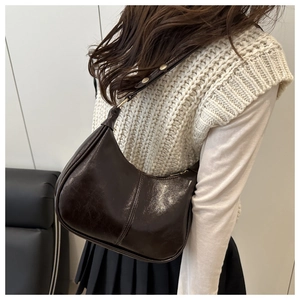 Close-up of a vintage brown leather crescent bag worn by a model in a urban style