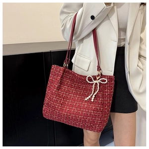 Detail der roten Tweed-Tasche mit Perlen-Schleifen-Anhänger und schmalem Schulterriemen