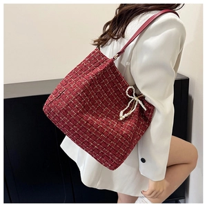 Detail der roten Tweed-Tasche mit Goldfaden-Webung und dekorativem Perlen-Schleifen-Anhänger