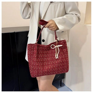 Detail der roten Tweed-Tasche mit Perlenbogen-Anhänger und Ledergriffen oben